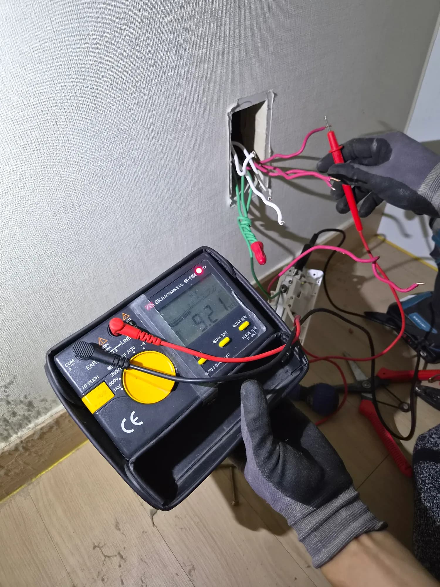 벽면 배선을 분리한 뒤 계측기로 회로 상태를 측정하는 모습
