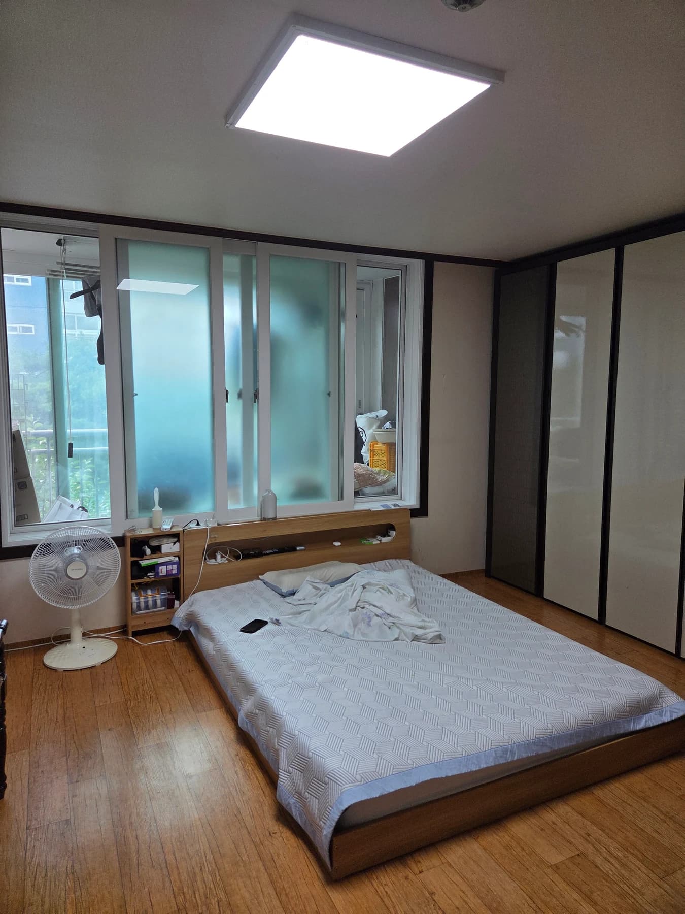 침대가 있는 방 천장에 설치된 사각 엣지 조명이 켜진 모습